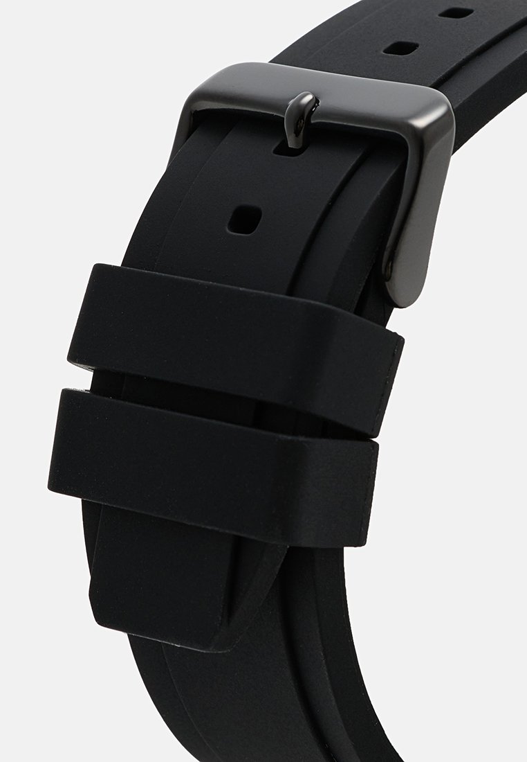 Correa de reloj de goma negra con acabado mate, cuenta con una hebilla de metal plateado y dos fijaciones ajustables. Diseño de hebilla estándar con múltiples orificios.
