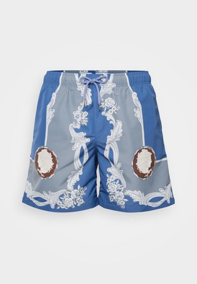 Shorts de bain bleus avec un motif floral blanc, dégradé bleu clair, taille élastique avec cordon de serrage, et accents de médaillons décoratifs.