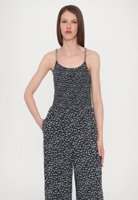 Jumpsuit floreale nero con spalline sottili, corpino arricciato, gambe larghe e tasche. Presenta un motivo floreale blu e bianco.