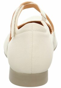 Chaussure en cuir de couleur crème avec un talon bas, dos ouvert et sangle réglable. Design simple avec une texture lisse et un minimum de détails.