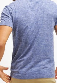 Blå melerad t-shirt med kort ärm och rund halsringning. Tyget har en mjuk textur och innehåller ett subtilt, ojämnt mönster.