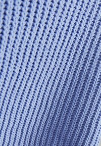 Tissu tricoté bleu clair avec une texture à côtes verticales espacées de manière homogène et un motif de points en boucle petits.
