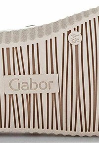 Semelle de chaussure blanche avec des lignes texturées verticales et un bord festonné, portant un petit logo Gabor et une étiquette de taille marquée 42.