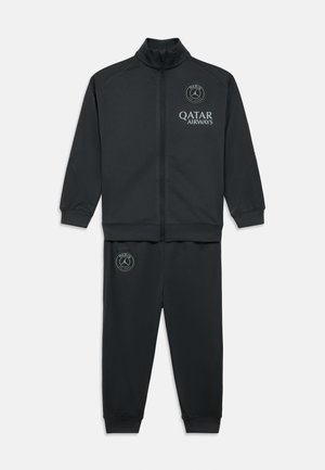 Svart atletisk treningsdress med en jakke med glidelås og matchende bukser. Begge har logoaksenter i grått. Glatt, elastisk stoff.