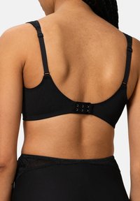 Reggiseno nero con spalline regolabili, tessuto morbido e chiusura con gancio e occhiello. Presenta un sottile accento in pizzo sul bordo.