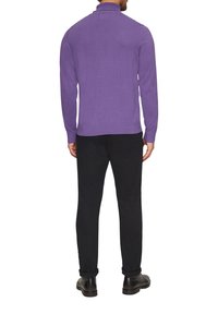 Paarse gebreide trui met een hoge kraag en lange mouwen, gecombineerd met zwarte broek en zwarte schoenen, gezien vanuit de rug.