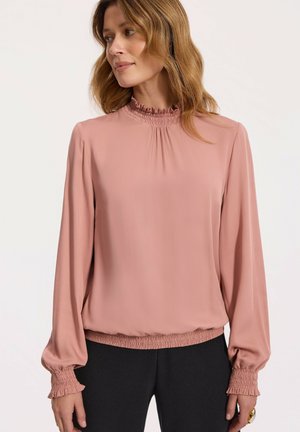 Różowa bluzka z długim rękawem, z falbaniastym wysokim kołnierzem, marszczonymi mankietami i luźnym krojem. Wykonana z gładkiego, lekkiego materiału.