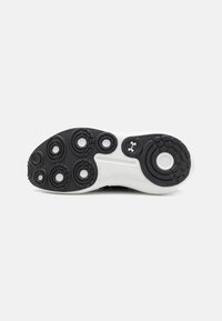 Black and white sneaker sole featuring circular traction patterns and a pronounced logo. The surface is textured with a smooth finish.