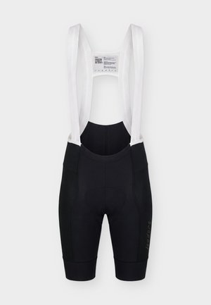 Fekete kerékpáros kantáros nadrág fehér hálós vállpántokkal és párnázott ülőfelülettel, fehér háttér előtt bemutatva.