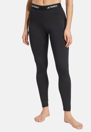 Mallas negras hechas de material elástico, con una amplia cinturilla elástica que lleva la marca "TERREX" y un diseño ajustado.