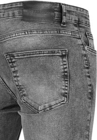 Jean en denim noir délavé montrant la poche arrière droite et une étiquette en cuir noir cousue sur la ceinture avec le texte "2Y PREMIUM".
