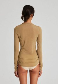 Beige Langarmoberteil mit glatter Textur, enganliegendem Schnitt und rundem Halsausschnitt. Verfügt über geraffte Details entlang des Rückens.