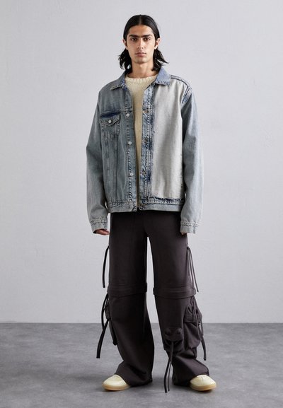 Light blue denim jacket with contrasting dark patches, cream knit sweater, black wide-leg cargo pants with side pockets, and cream sneakers.