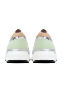 Paire de baskets avec des détails verts, beiges et argentés vues de dos, avec des semelles blanches épaisses et des semelles extérieures noires.