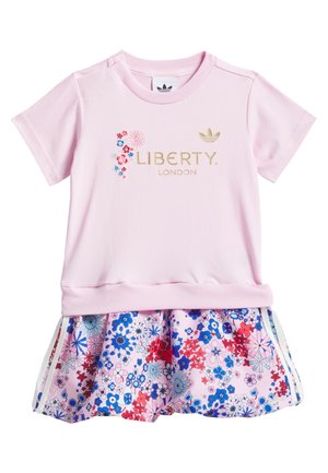 Różowy top z krótkim rękawem z napisem "Liberty London" w złotym kolorze oraz małymi kwiatowymi akcentami, zestawiony z kwiecistą spódnicą w różowo-niebiesko-czerwonym wzorze.