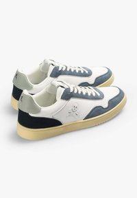Weiße und marineblaue Sneakers aus Wildleder und Leder, mit perforierten Details, einem Totenkopf-Logo und einer Gummisohle.