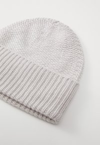 Gorro de punto gris claro con una banda acanalada. Textura suave con un patrón uniforme y sutiles detalles de costura.