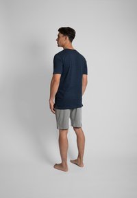 Navy striped T-shirt with short sleeves, paired with light gray shorts. The fabric appears soft with a relaxed fit.