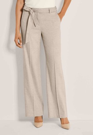 Beige hoch taillierte, weit geschnittene Hose mit gebundenem Stoffgürtel, getragen mit beigen spitzen Pumps und einem weißen Oberteil.