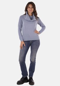 Maglione lavorato a maglia di un blu chiaro con collo a caduta, orlo e polsini a costine. Abbinato a jeans blu scuro e stivaletti neri con lacci.