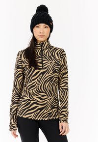 Maglia a maniche lunghe con zip in fantasia zebra, caratterizzata da una base beige con svolazzi neri. Indossata con un berretto in maglia nera testurizzata.