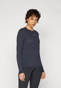 Langarm-Sportshirt in Dunkelblau, aus glattem, feuchtigkeitsableitendem Material gefertigt. Verfügt über einen Rundhalsausschnitt und ein dezentes Logo in der Mitte.