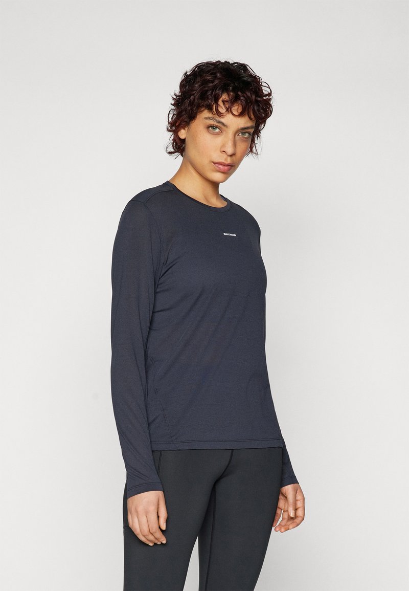 Langarm-Sportshirt in Dunkelblau, aus glattem, feuchtigkeitsableitendem Material gefertigt. Verfügt über einen Rundhalsausschnitt und ein dezentes Logo in der Mitte.