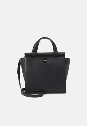 Sac à main structuré noir avec poignées supérieures, détail de fermoir doré et bandoulière détachable sur fond clair uni.