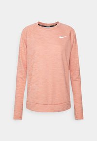 Rosa långärmad atletisk topp med raglanärmar, släta texturerade tyg och en liten vit Nike-logga på bröstet; rundad halsringning.