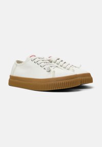 Sneakers in tela off-white con suola in gomma testurizzata. Presentano una punta rotonda, lacci piatti e accenti rossi vicino alla linguetta.
