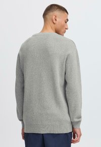 Grauer Strickpullover mit Rundhalsausschnitt, langen Ärmeln und gerippten Bündchen sowie Saum. Weicher Textur, schlichtes Design und lockere Passform.
