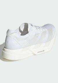 Baskets de course blanches avec une tige texturée, des lacets lisses et une semelle épaisse et légère marquée "LIGHTSTRIKE PRO".