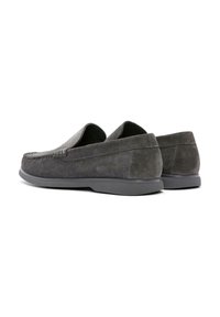 Mocassins en daim gris avec un bout arrondi, des semelles en caoutchouc plates et des coutures contrastantes le long des coutures. Design simple avec une texture lisse.