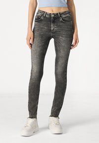 Jeans skinny en denim noir au look délavé, avec cinq poches et passants de ceinture. Coupés pour un ajustement serré, avec une légère élasticité pour le confort.