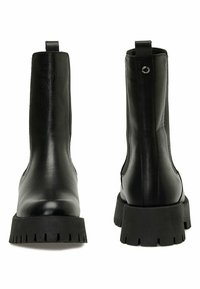 Botas negras de cuero hasta el tobillo con suelas de goma acanaladas, paneles laterales elásticos y tiradores; textura suave y diseño elegante con un estilo minimalista.