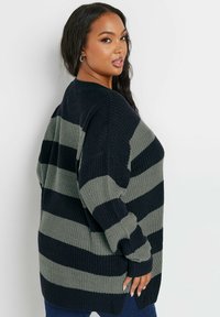 Randig stickad tröja i mörk marinblå och olivgrön färg. Lös passform med långa ärmar, bred halsringning och sidofickor för komfort.