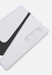 Tarjetero de cuero blanco y negro con un diseño geométrico, que presenta tres recortes, texturas contrastantes y costura blanca.