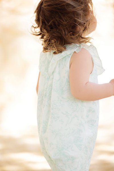Light green floral-patterned romper with a ruffled collar, made of soft fabric, featuring sleeveless design and a relaxed fit.