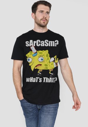 Schwarzes Baumwoll-T-Shirt mit einem bunten SpongeBob Schwammkopf-Graphic und dem Text "sArCaSm? Was ist das?" in fetter, verwitterter Schrift.