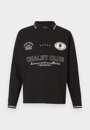Mustade pikkade varrukatega polo särk valge tekstiga "CHALET CLUB" ja plaastritega, triibuline krae ja mansetid, juhuslik vabaaja stiil.