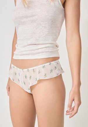 Durchsichtige Panties aus floral gemustertem Stoff mit frilligem Saum, versehen mit kleinen grünen und lila Blumen auf einem hellen Hintergrund.