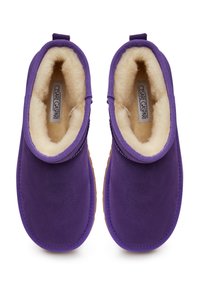 Chaussons violets avec une doublure en polaire douce de couleur crème, bout arrondi et languette à l'arrière. Semelle texturée pour une meilleure adhérence.