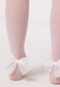 Helle rosa Netzstrumpfhosen mit einer strukturierten Oberfläche, die große weiße Netzschleifen am Knöchel für zusätzlichen Detailreichtum aufweisen.