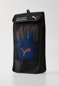 Puma Ultra kapuskesztyűk kék színben, piros és szürke díszítéssel, átlátszó fekete hálós táskába csomagolva, tetején fedéllel.