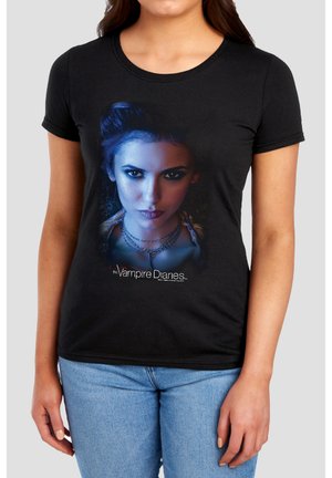 Woman wearing black T-shirt with intense female face graphic lit in blue and text "The Vampire Diaries" at the bottom center.