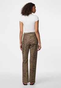 Pantaloni cu imprimeu leopard dintr-un material moale, având un design cu picior drept și talie medie. Completați cu un top alb simplu, ajustat.