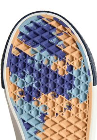 Podešev boty s texturovaným vzorem z modré a fialové gumy přes oranžový základ, vykazující známky opotřebení a šupinění.