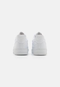 Nike Air Force 1 tossud täielikult valge värviga, sujuva nahast pealisega, tõstetud roosi kujundusega kandadel ja tekstureeritud kummist tallaga.