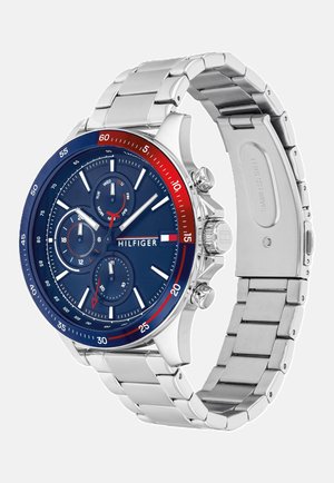 Náramkové hodinky Tommy Hilfiger z nerezové oceli s modrým ciferníkem, červenomodrým lunetou, třemi subciferníky a stříbrným náramkem.