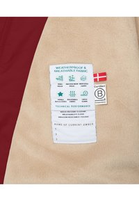 Etiqueta de tejido impermeable en un forro polar beige con acentos color marrón burdeos, que incluye instrucciones de cuidado y detalles de rendimiento como la presión del agua y la transpirabilidad.